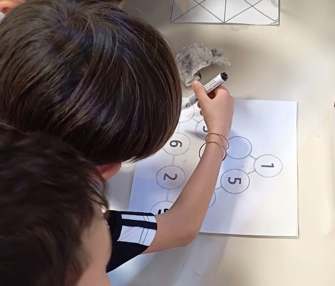 Bambini scrivono dei numeri sui lati di un triangolo. Bambini scrivono dei numeri sui lati di un triangolo.