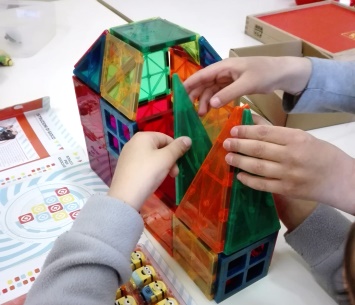 Bambino costruisce una casa con forme geometriche di plastica