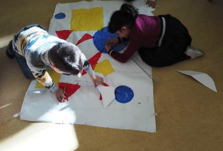 Bambini realizzano un grande quadro con forme geometriche Bambini realizzano un grande quadro con forme geometriche