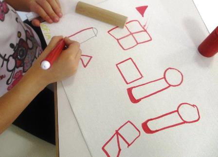 Bambino disegna alcuni solidi su un grande foglio