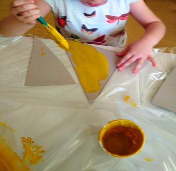 Bambina colora triangoli di cartoncino con la tempera Bambina colora triangoli di cartoncino con la tempera